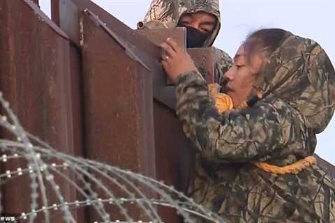 Dozens of illegal immigrants in camouflage clothes climb the border wall with ropes